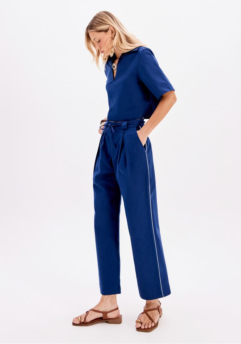 Modelo vestindo calça reta azul com faixa para amarração, vista lateral.