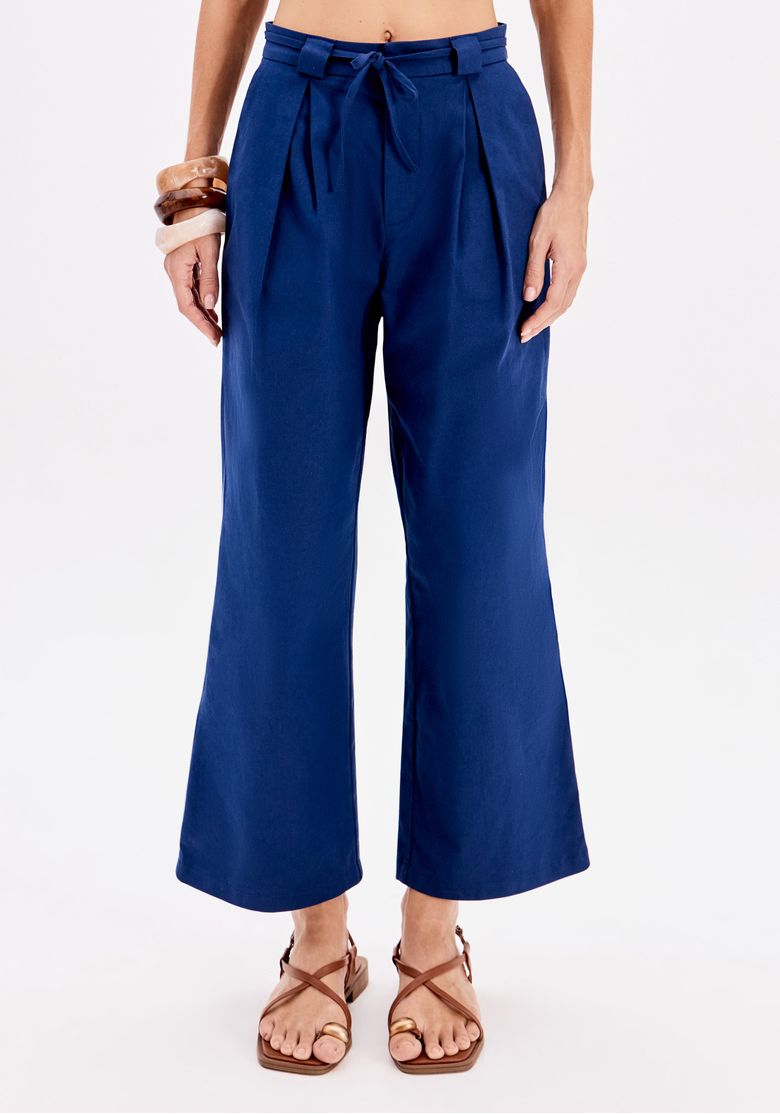 Vista frontal da calça azul com pregas e faixa para amarração.
