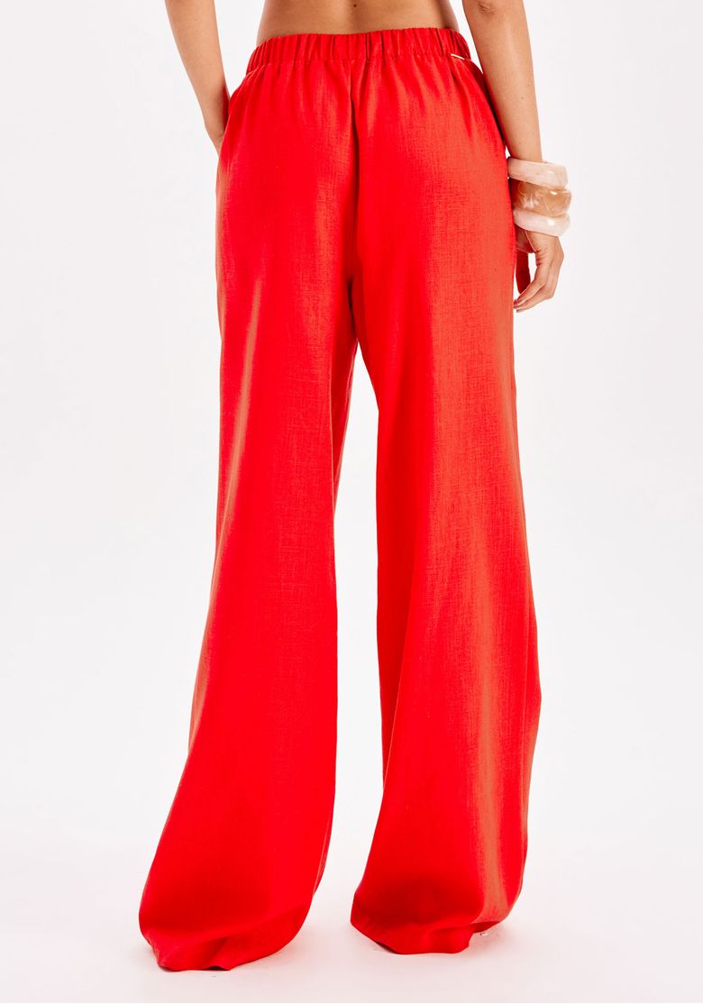 Conjunto vermelho vista de costas com calça reta comprida e top de alças finas em estúdio