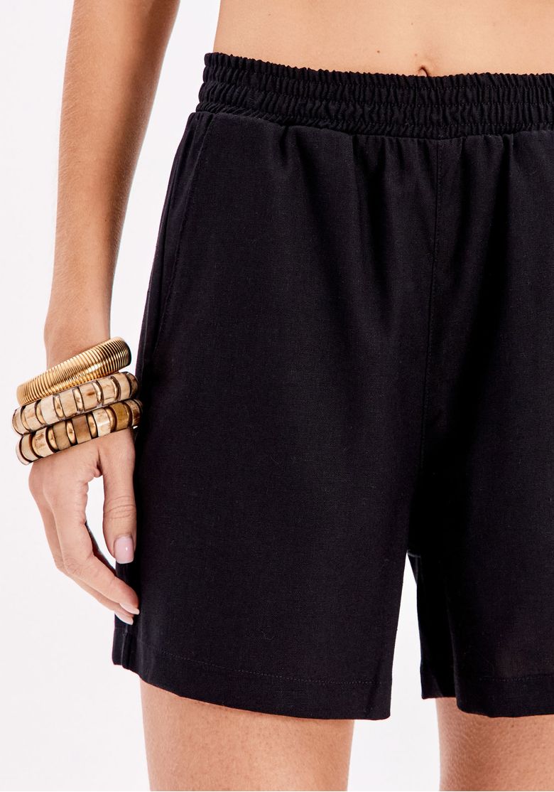 Detalhe do cós elástico do short preto, mostrando o acabamento.