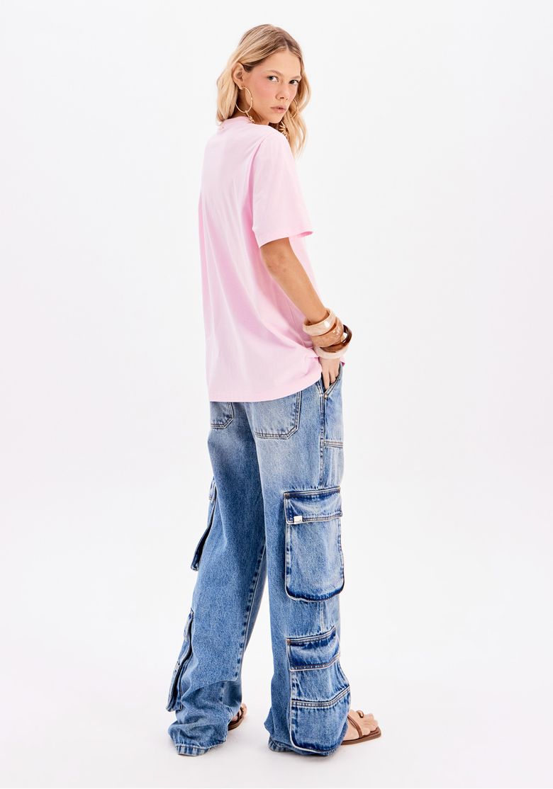Vista traseira da camiseta oversized rosa com estampa de biquíni, mostrando o comprimento alongado e o caimento solto.