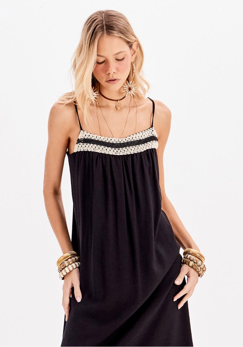Modelo usando vestido super midi preto com caimento solto e recorte reto, detalhe franzido discreto abaixo do busto