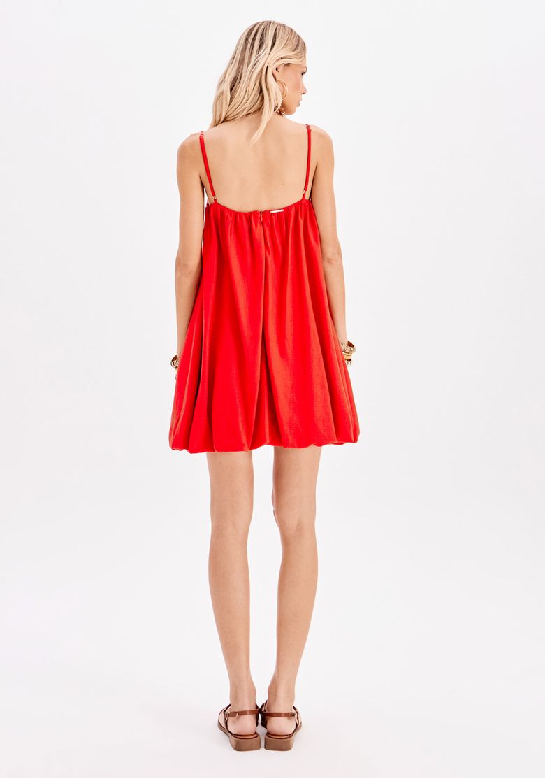 Modelo usando o vestido balonê vermelho em um ambiente descontraído.