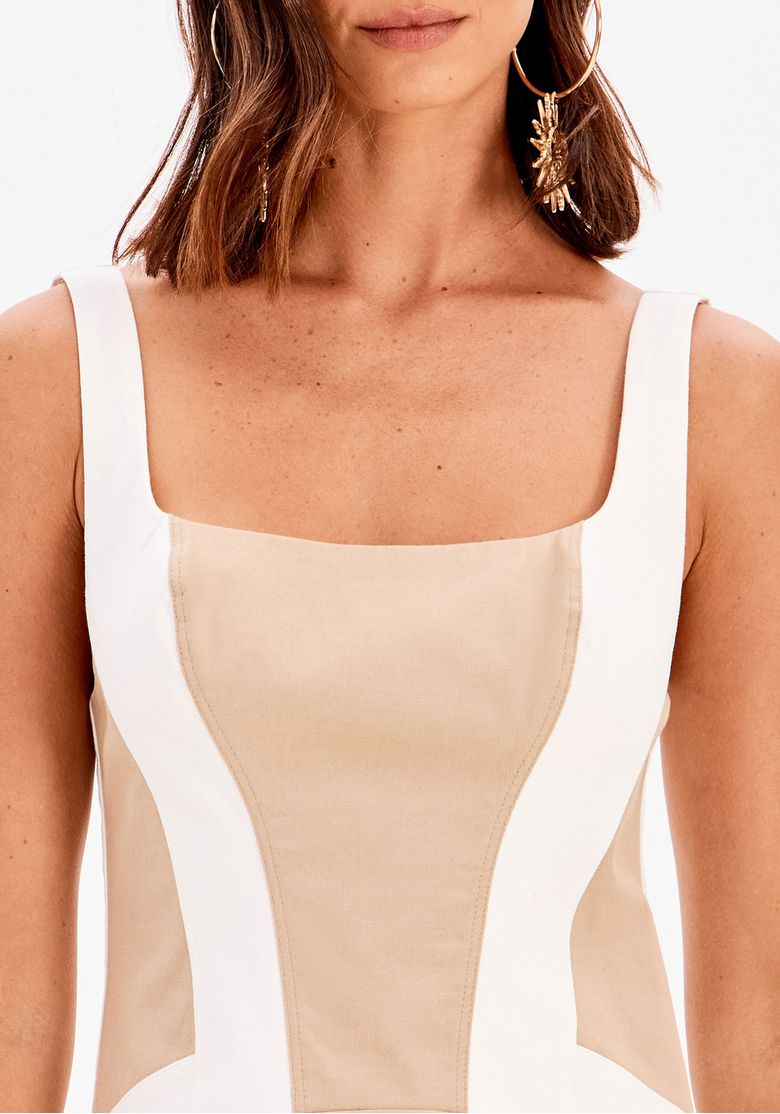 Vestido super midi bege com recortes brancos, visão meia frente destacando modelagem acinturada e acabamento do tecido