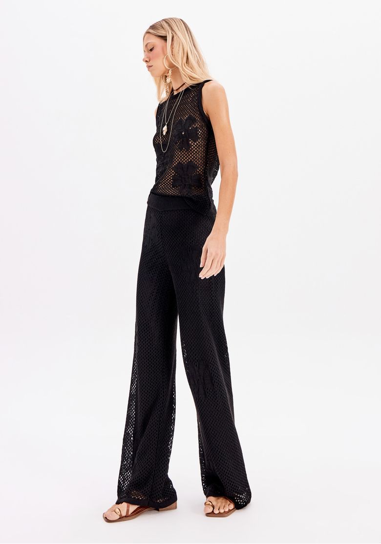 Modelo de costas usando calça tricô preta com cós alto e detalhes vazados na trama