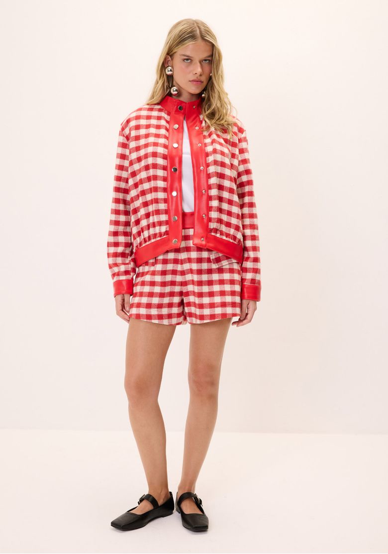 Modelo vestindo short xadrez vichy vermelho e branco com jaqueta combinando.