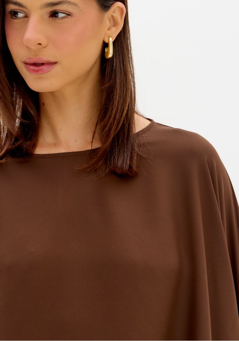 Close da blusa cropped capa marrom com decote canoa e tecido leve de caimento sofisticado
