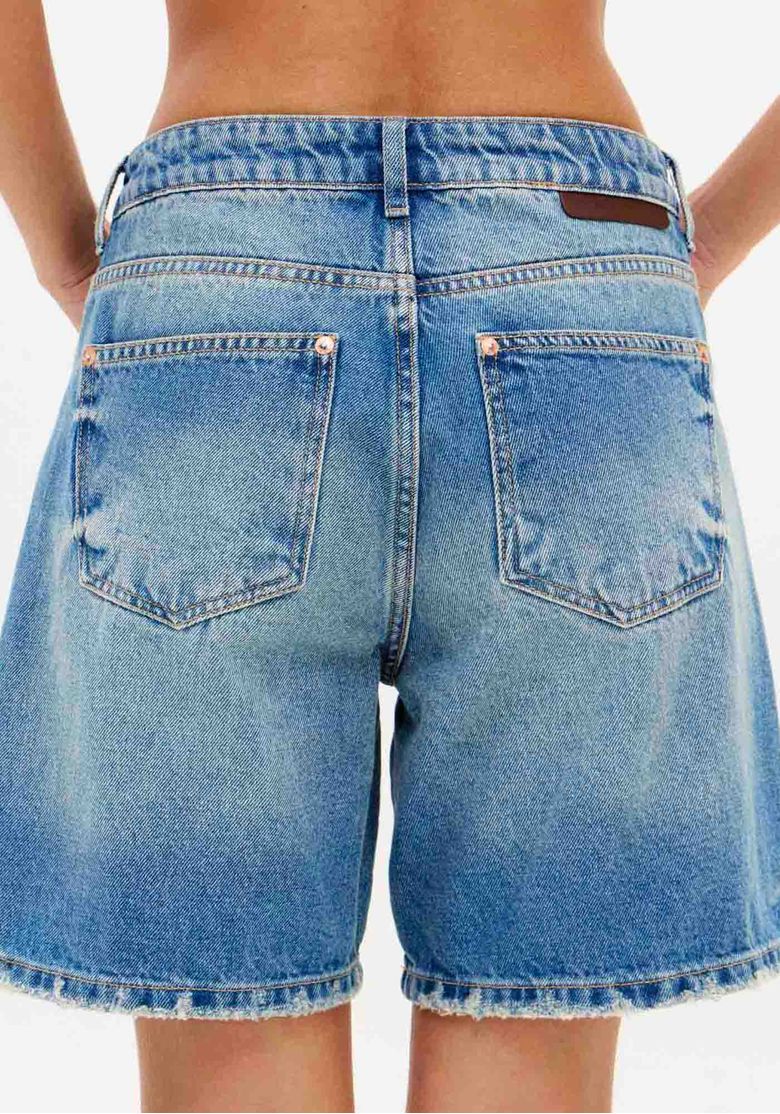 Detalhe traseiro da bermuda jeans, evidenciando os bolsos funcionais e o acabamento do denim.
