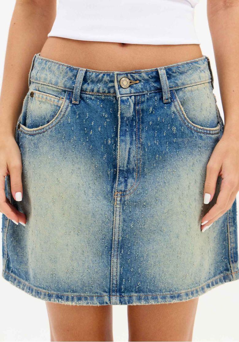 Detalhe frontal da saia jeans curta com bolsos e lavagem diferenciada.
