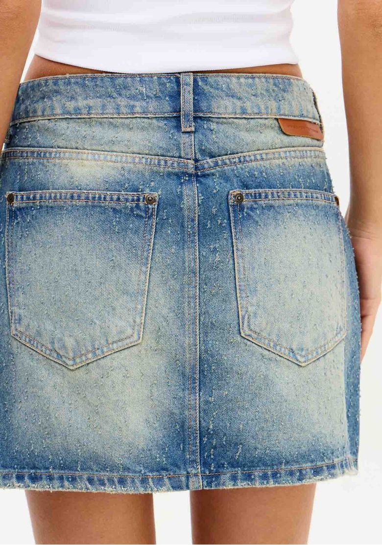Vista traseira da saia jeans curta com bolsos e acabamento em denim.