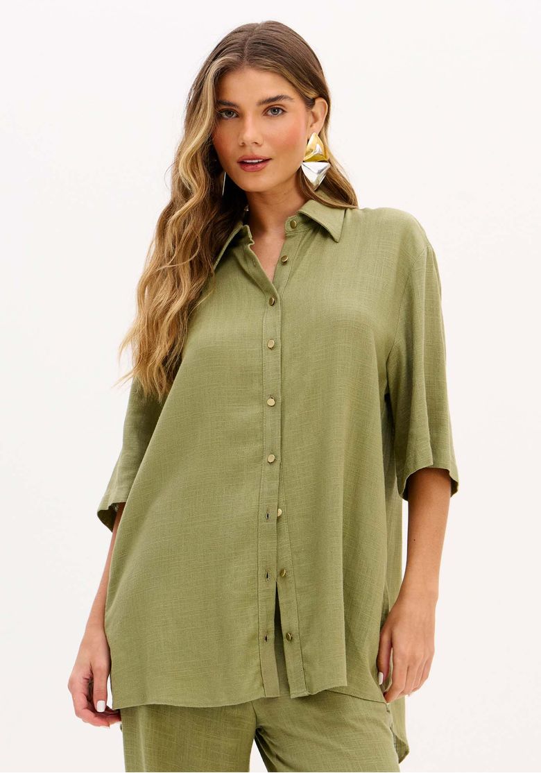 Modelo usando camisa feminina oversized alongada com linho em tom verde oliva e calça ampla coordenada, look casual urbano de verão