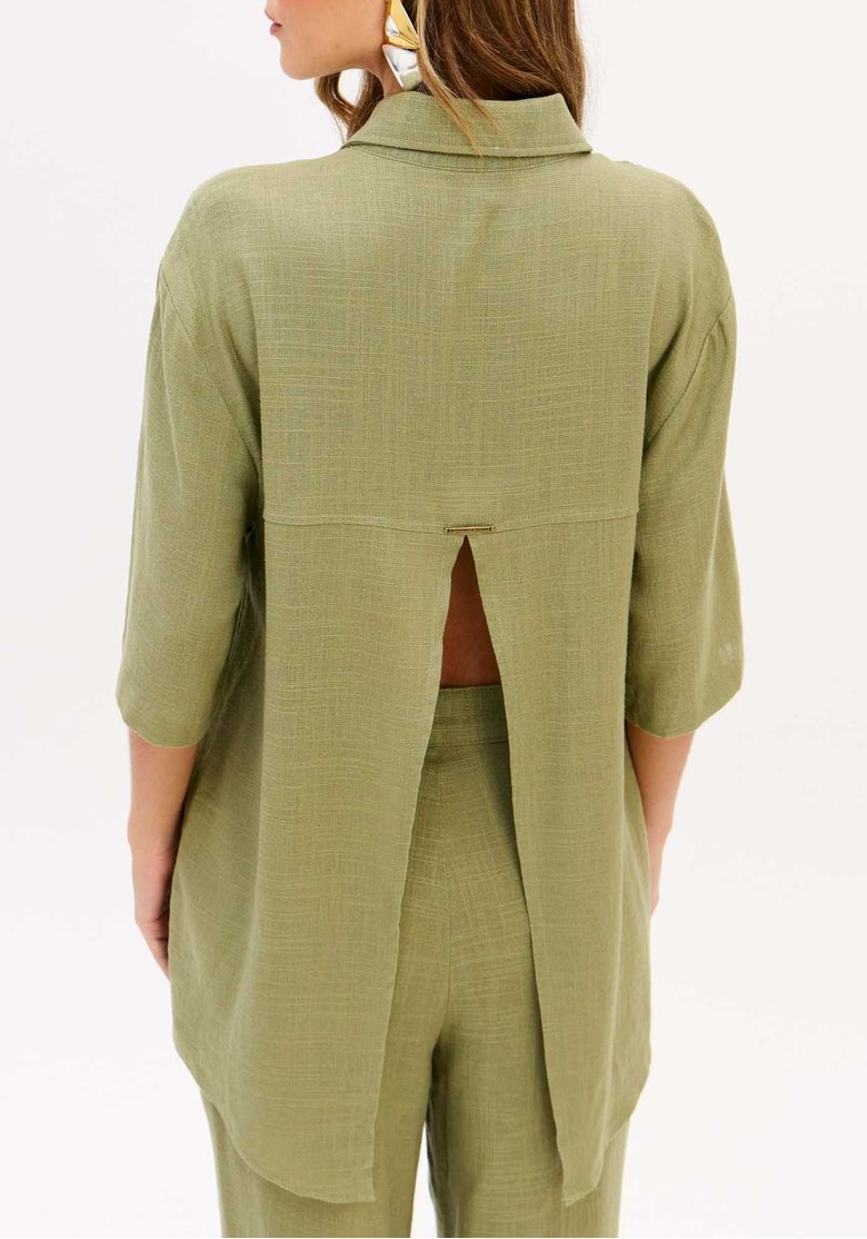 Vista traseira da camisa feminina oversized com linho em verde oliva, destacando a abertura nas costas e o comprimento alongado