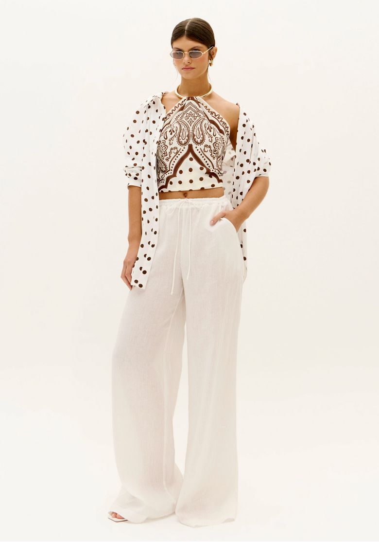 Look feminino com calça wide leg branca de linho e camisa estampada aberta, mostrando caimento amplo e sofisticado