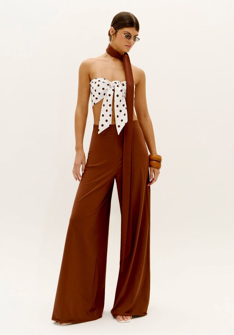 Modelo vestindo top faixa estampado com poá e calça marrom, vista frontal.