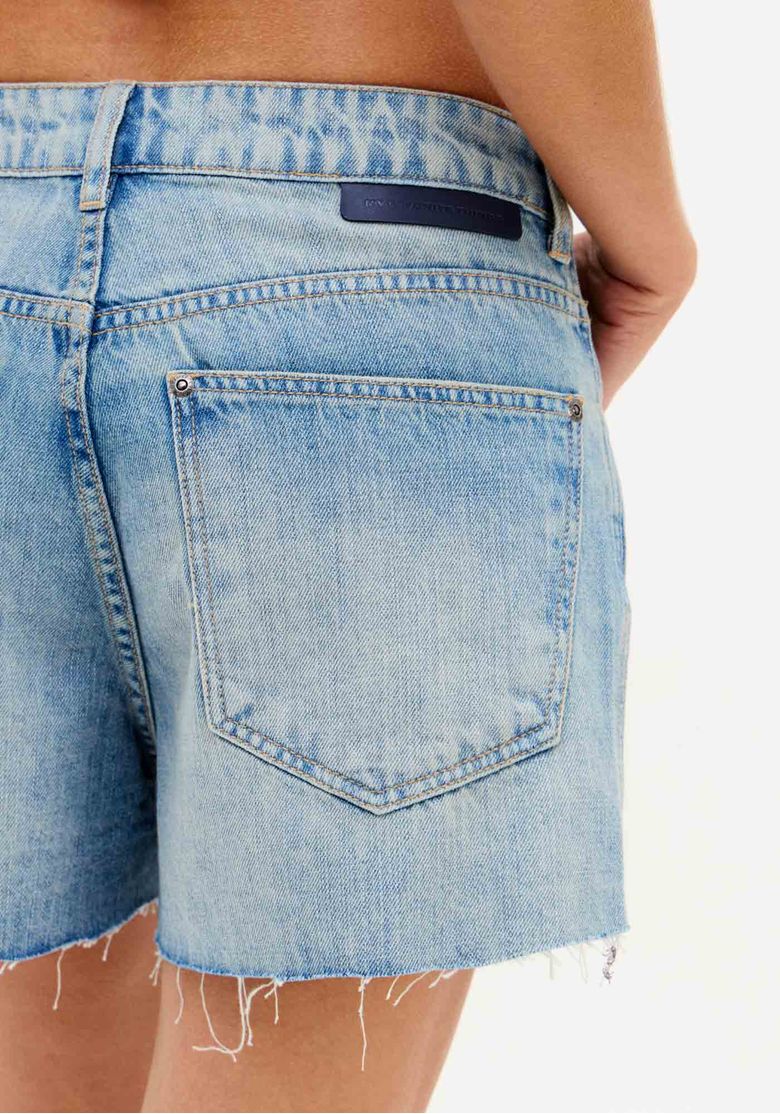 Detalhe do bolso traseiro do short jeans azul claro feminino com modelagem relaxed e acabamento desfiado na barra