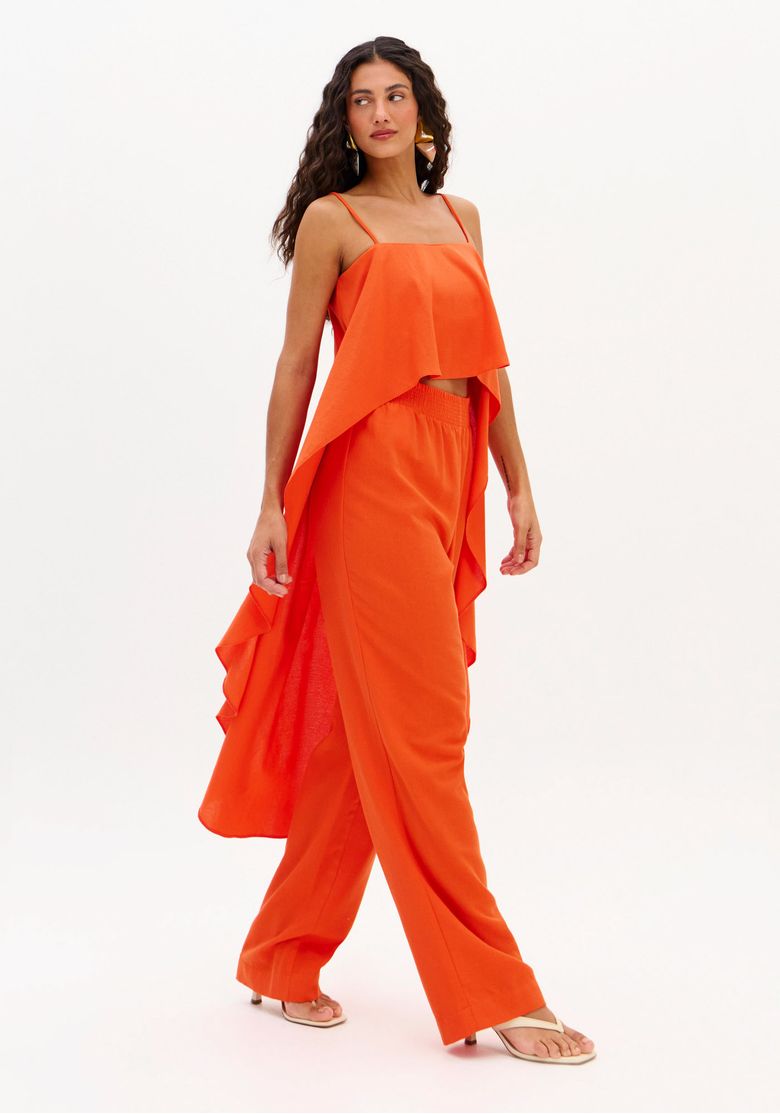 Conjunto feminino vermelho vista lateral em movimento: calça reta cintura média em tecido plano leve e top sobreposto com drapeado