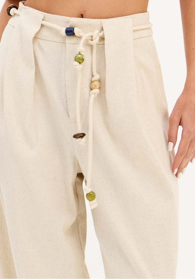Modelo caminhando com calça reta em linho bege, look leve e elegante para o verão
