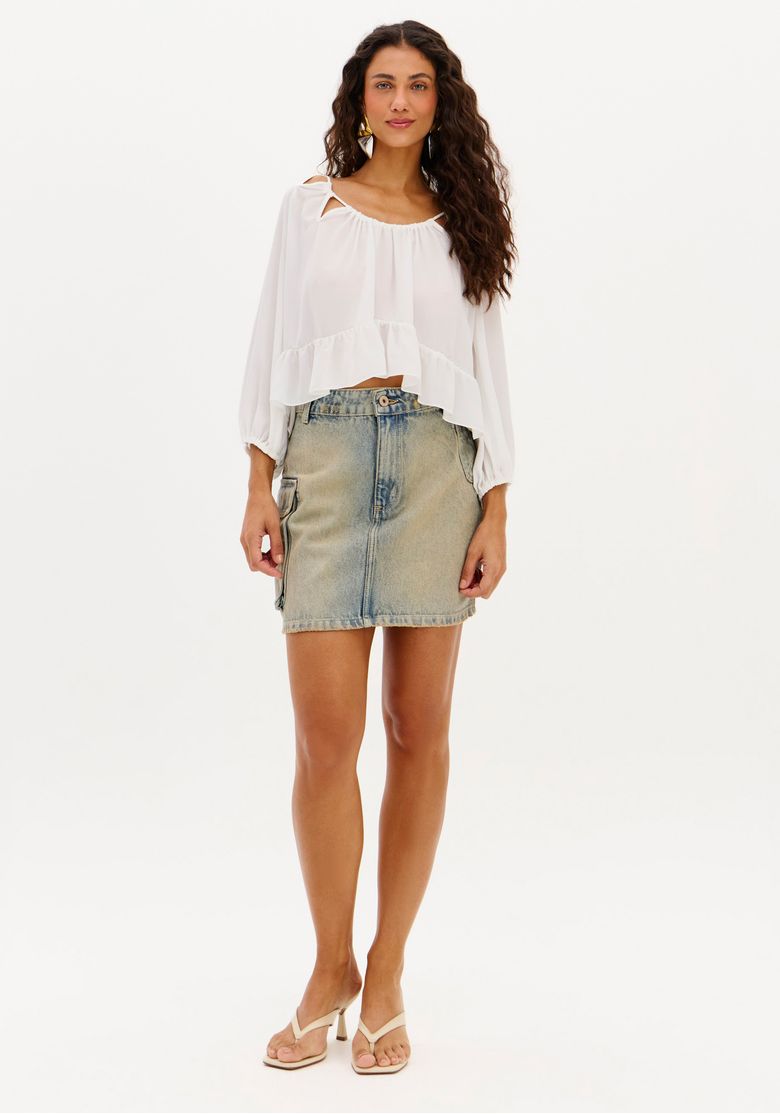 Mulher usando saia jeans curta cargo cintura alta vista frontal, denim azul e blusa branca, look urbano casual