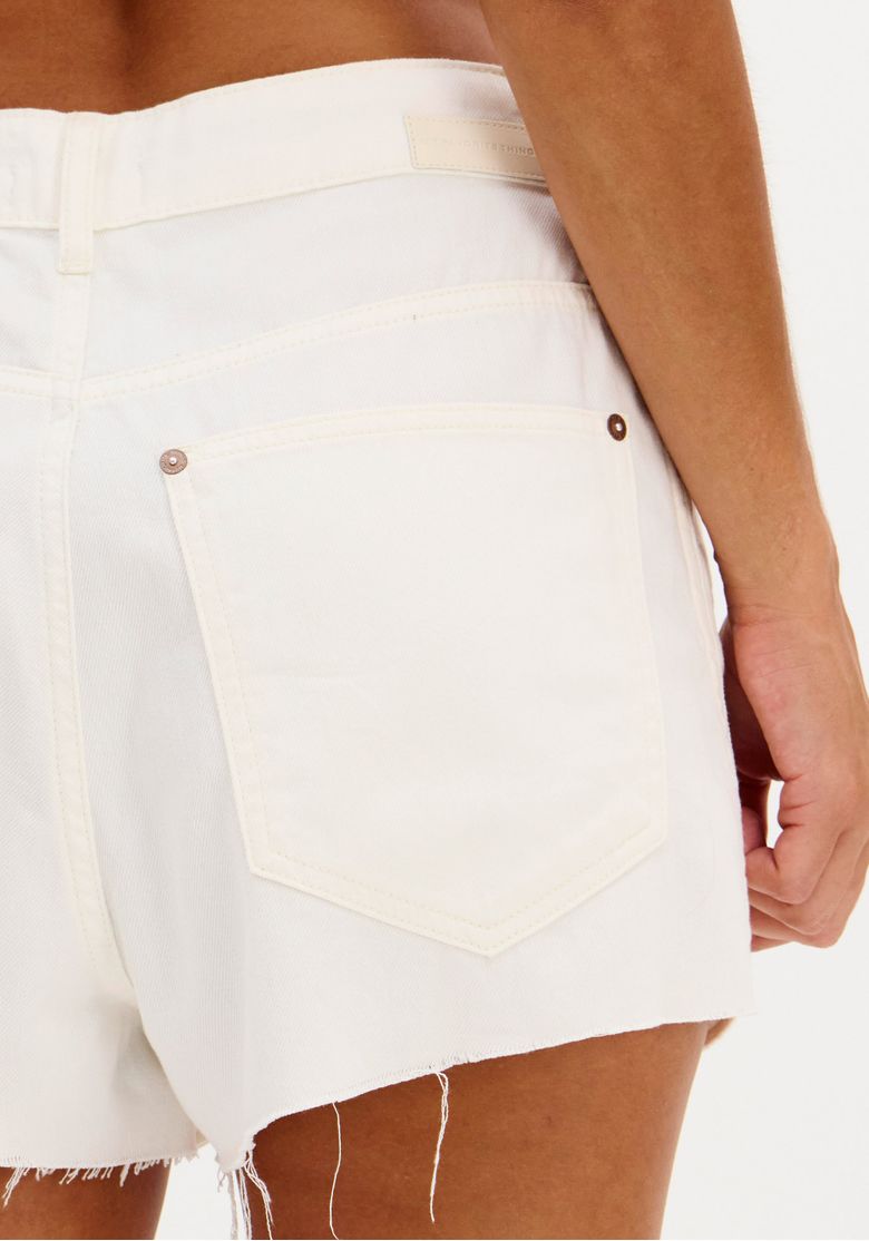 Close no bolso traseiro do short mom branco em sarja, mostrando o detalhamento da costura e acabamento da barra.