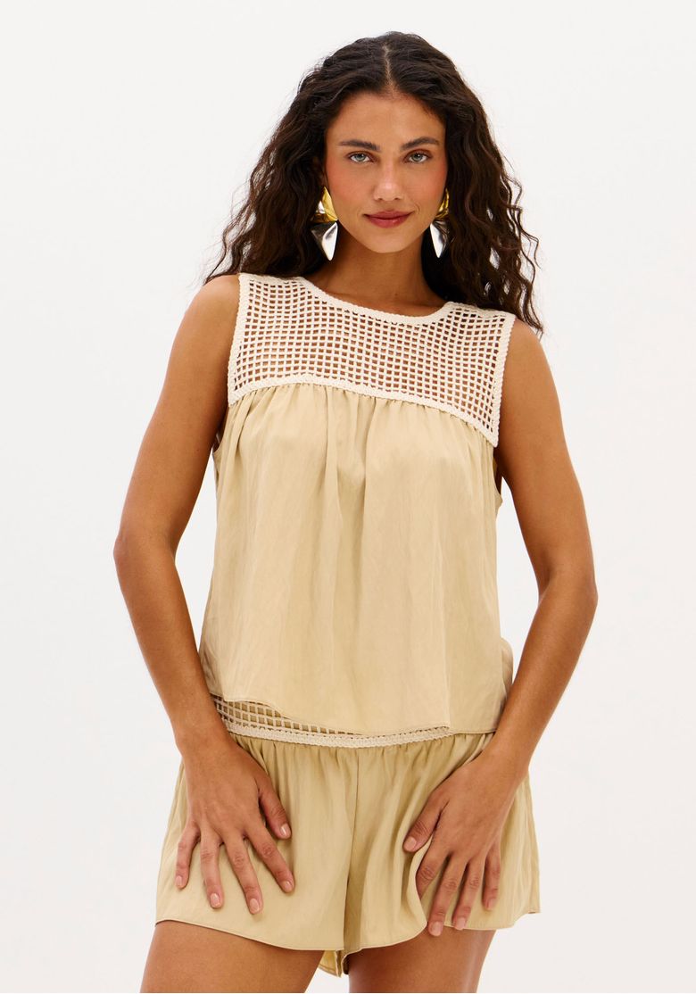 Frente da blusa bata bege com painel em crochê no decote e caimento solto, modelo em pé.