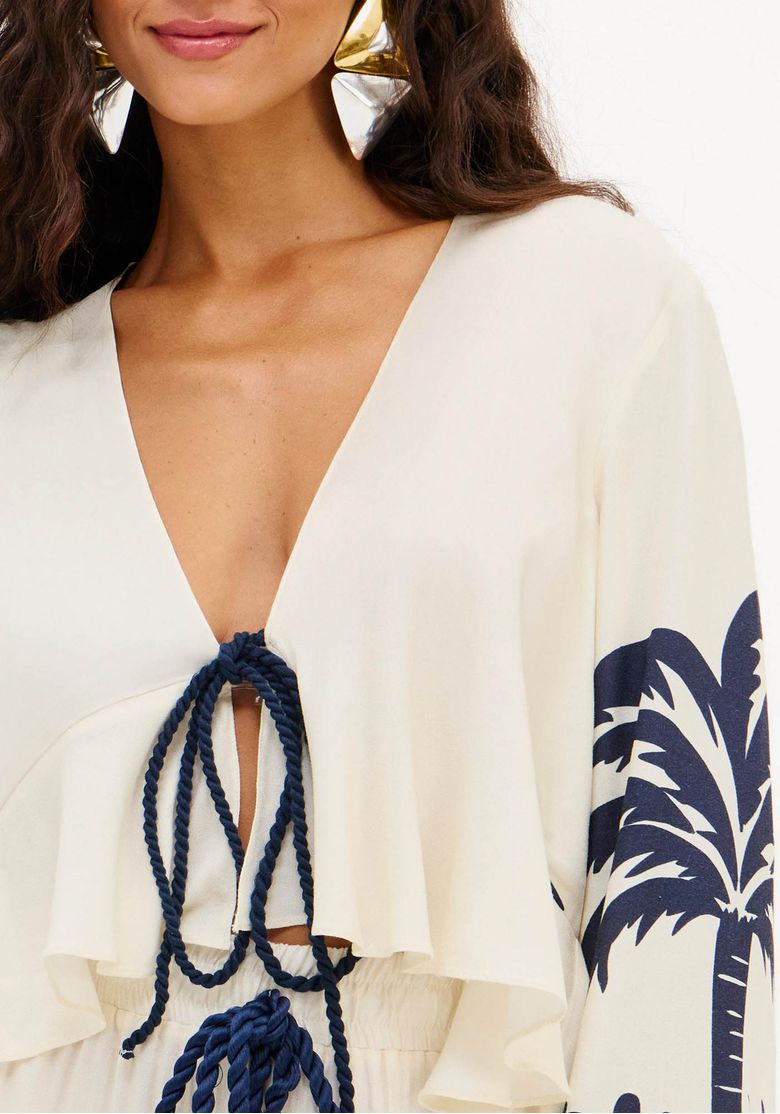 Close da blusa feminina estampada com decote em V profundo e amarração em cordão trançado azul, destacando o caimento fluido