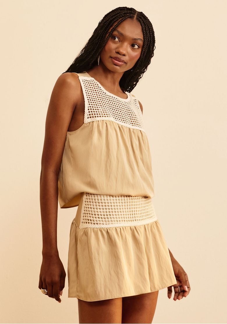 Modelo usando a blusa com saia bege e cós em crochê, alternativa de styling.