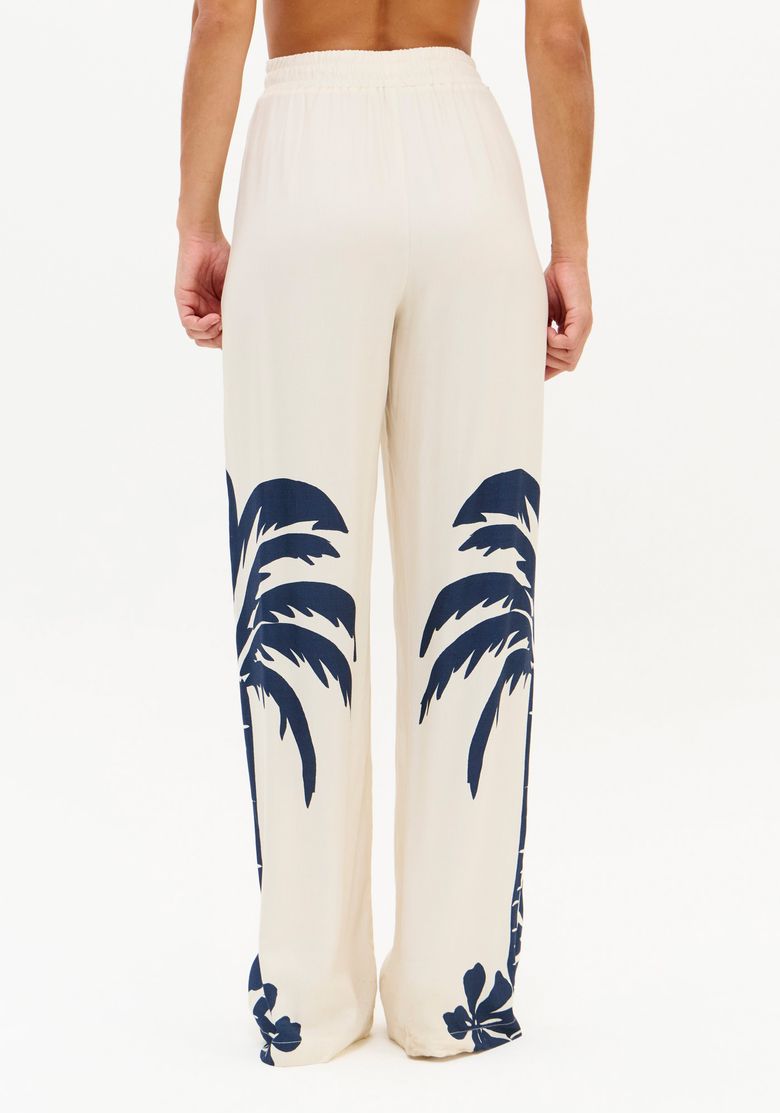 Vista traseira da modelo vestindo a calça longa com estampa tropical.