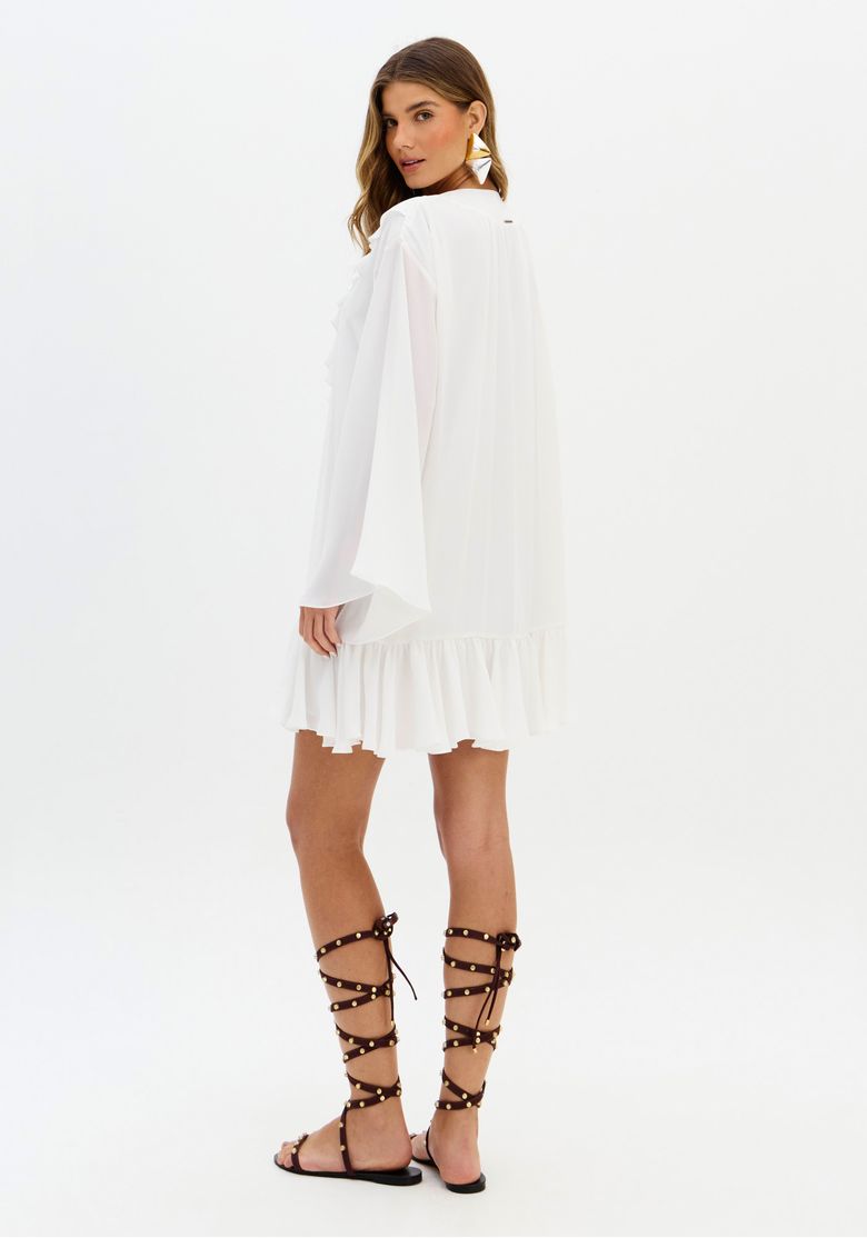 Close frontal do vestido branco com babados no decote e amarração, destacando o movimento e o acabamento da barra