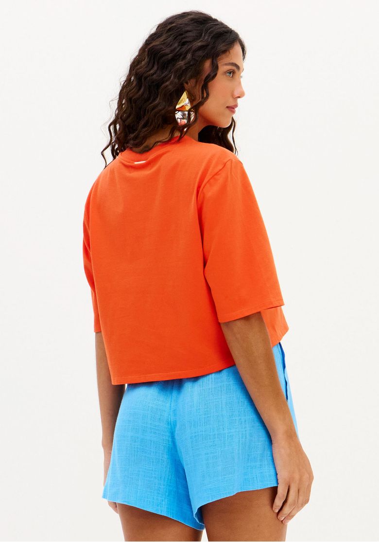 Vista lateral da t-shirt oversized cropped vermelha, destacando o caimento solto.