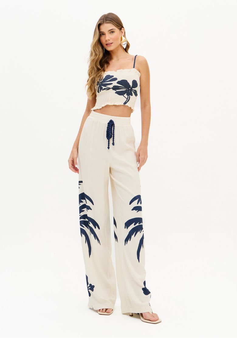 Modelo vestindo o conjunto com top cropped e calça estampada, em pose completa.