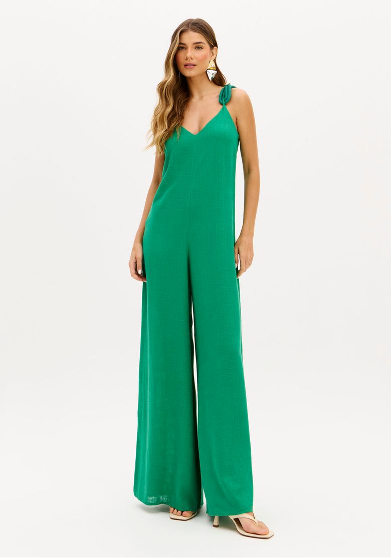 Modelo usando macacão pantalona verde com alças finas, decote V e barra longa