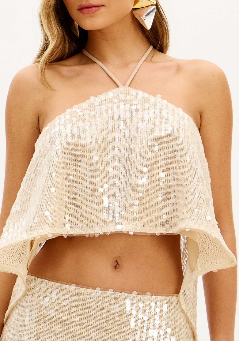 Close da blusa cropped bege com paetês, modelagem fluida e amarração no pescoço