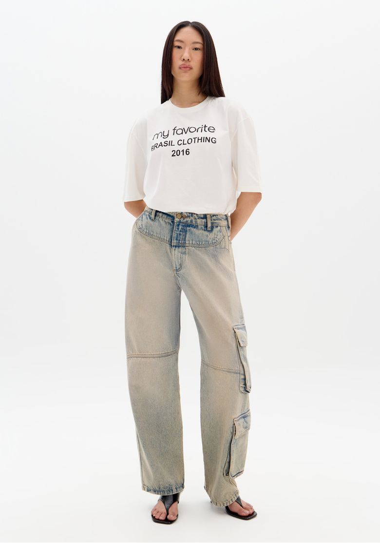 Modelo vestindo calça jeans baggy com lavagem estonada e camiseta branca.