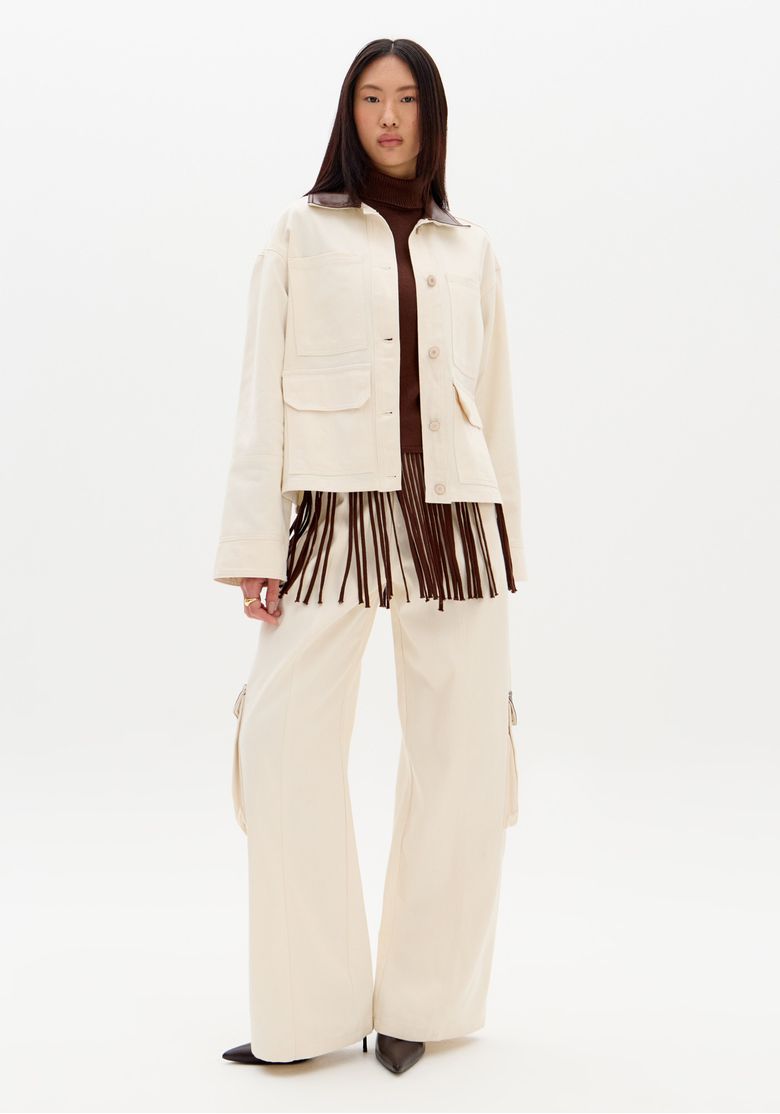 Modelo usando calça sarja wide leg bege cintura média com jaqueta curta bege e gola marrom, visual utilitário contemporâneo