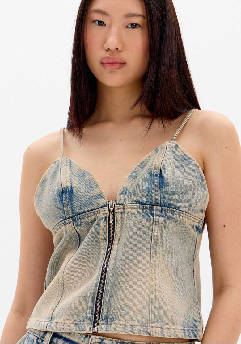 Detalhe do decote em V e recortes da blusa jeans.