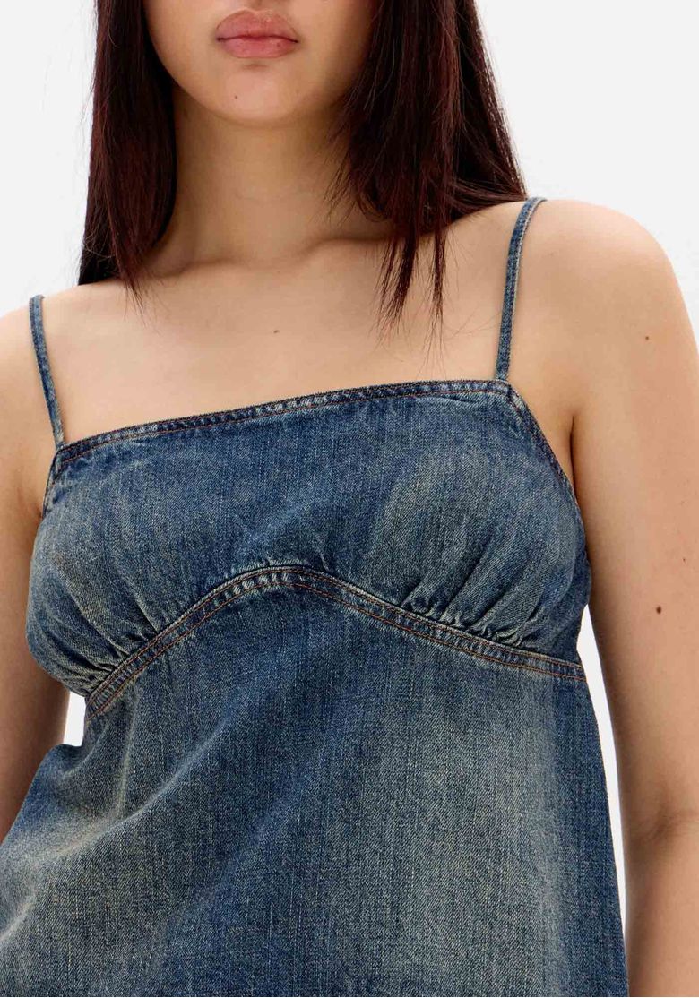Blusa jeans com recorte anatômico e leve franzido, detalhe próximo.