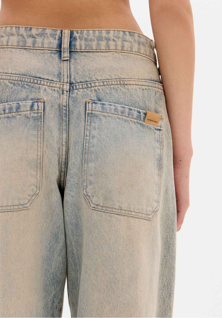 Detalhe do cós e passantes da calça jeans baggy.