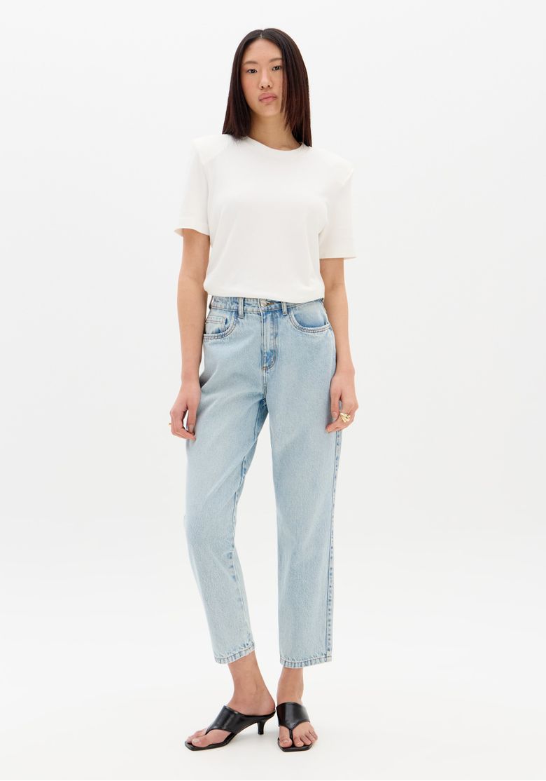 Modelo usando calça mom jeans cintura alta azul claro vista frontal com camiseta branca e sandália, look urbano e descomplicado