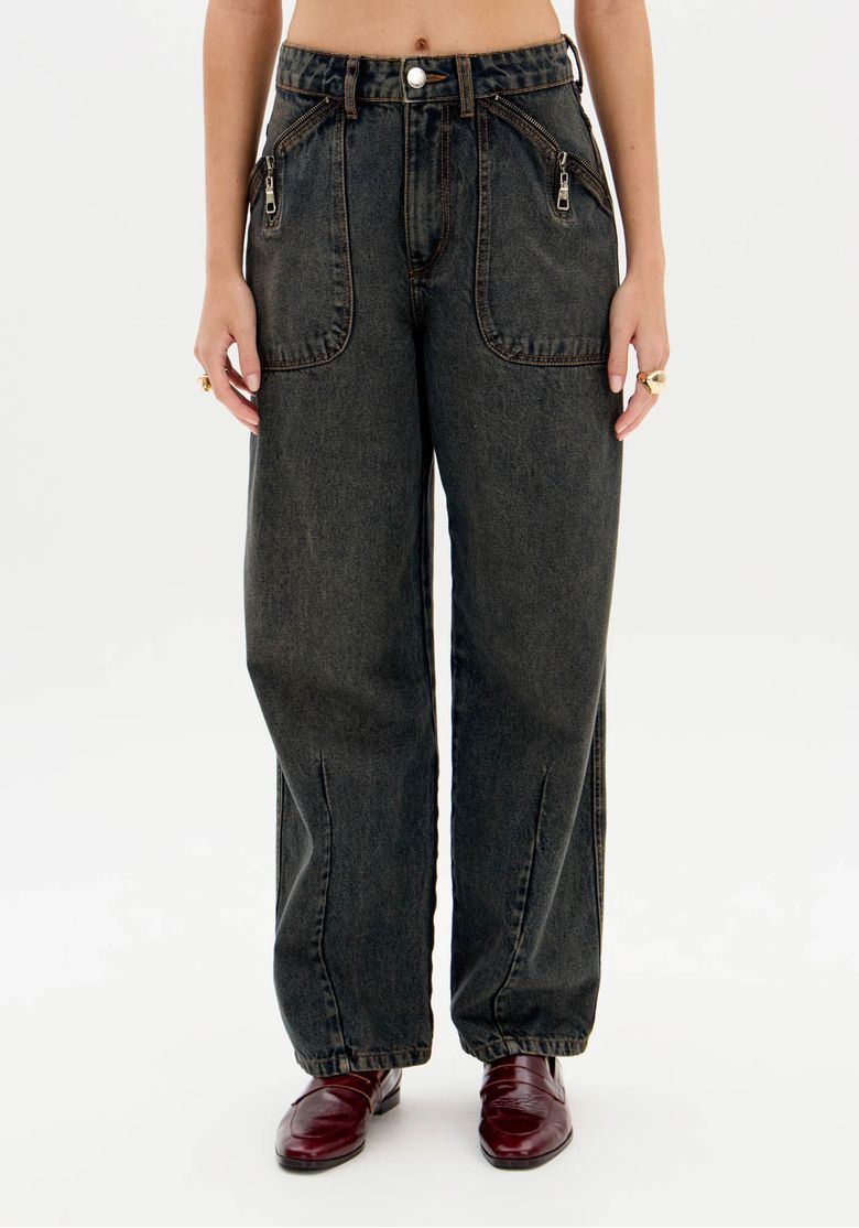 Detalhe frontal da calça baggy destacando cós com passantes, botão e bolsos chapados com zíper em denim escuro.