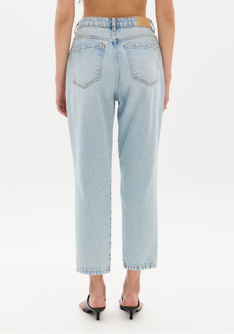 Close traseiro da calça mom jeans mostrando costura, bolsos e etiqueta no cós em denim claro