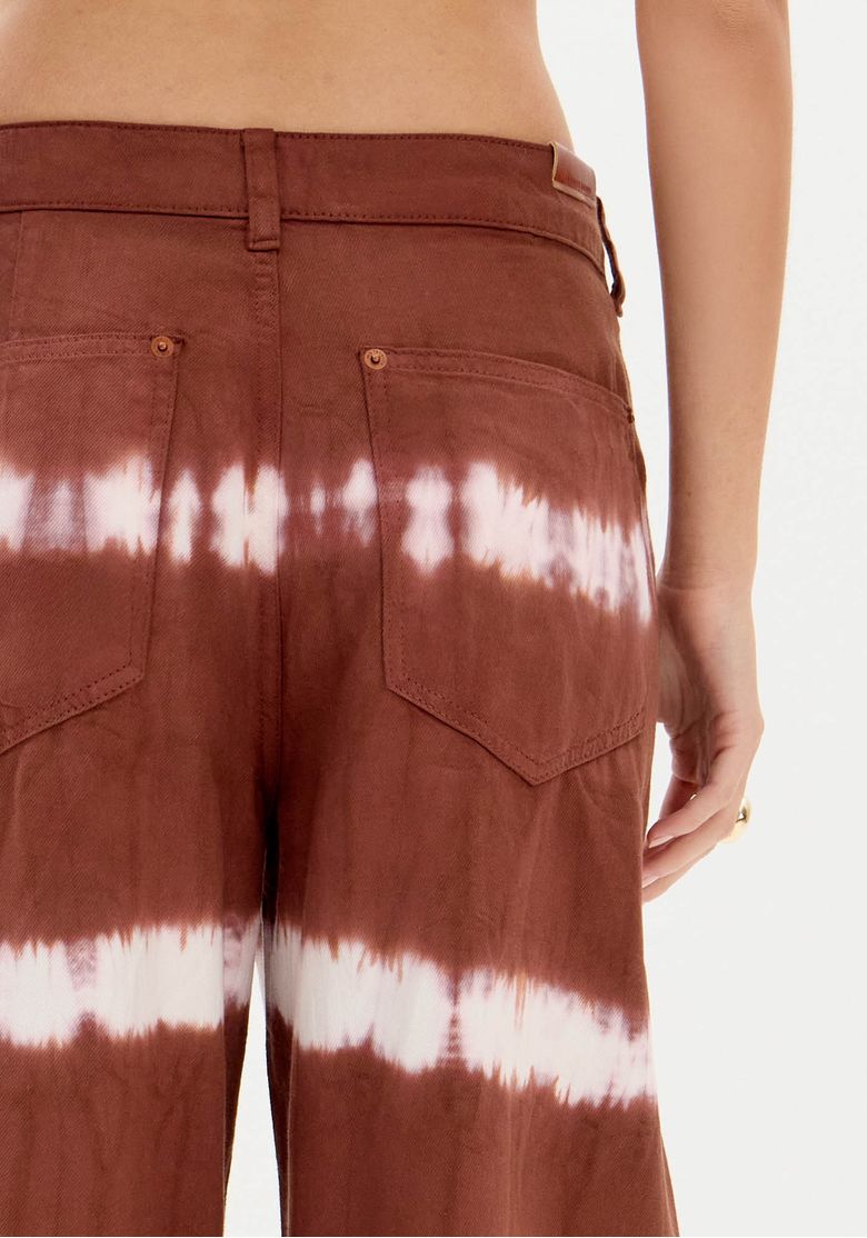 Close-up dos bolsos traseiros e do cós da calça sarja tie dye marrom com costura e textura do tecido 100% algodão