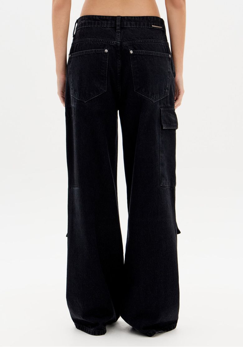 Modelo de costas com camiseta branca usando calça jeans preta full length, comprimento longo e caimento solto