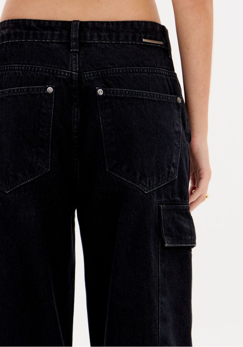 Detalhe do bolso cargo lateral com aba e costura reforçada na perna da calça jeans preta