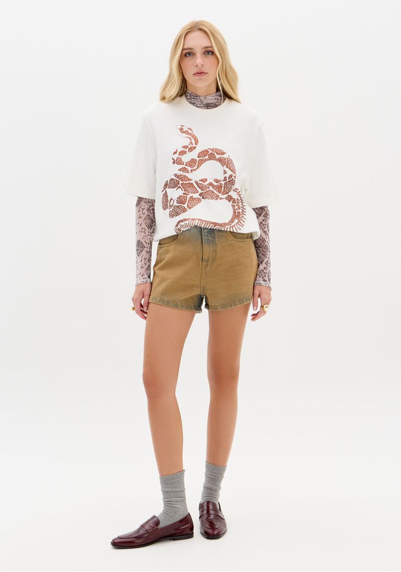 Modelo vestindo short jeans relaxed com lavagem azul e bege, combinado com camisa branca.
