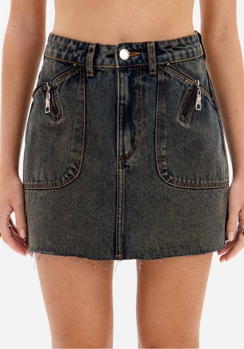 Detalhe frontal da saia jeans curta em denim escuro mostrando bolsos aplicados com zíper, cós com passantes e botão metálico.