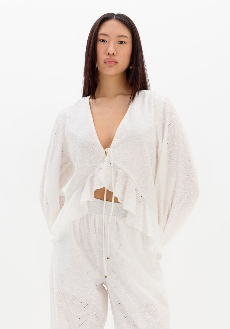 Blusa laise branca vista frontal em modelo, decote em V com amarração e babados na barra, mangas longas bufantes, look boho chic
