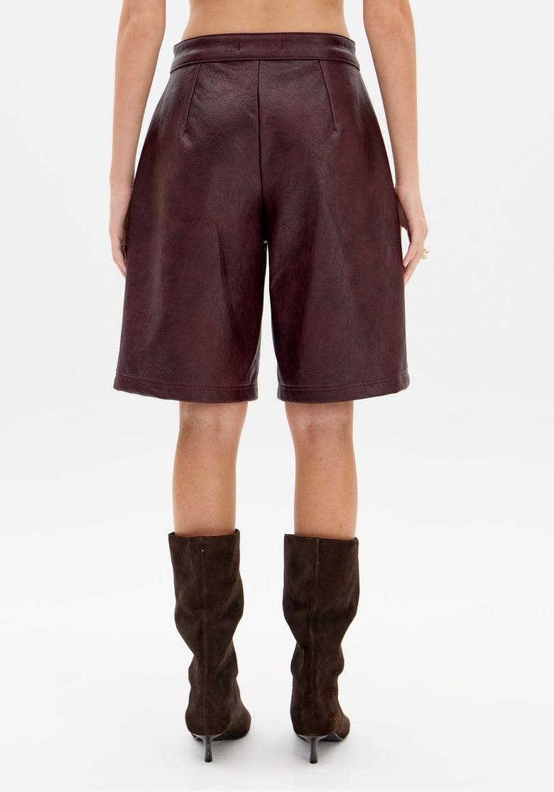 Modelo em pé usando bermuda utilitária vinho com camiseta listrada cinza, bolsos frontais visíveis e caimento regular