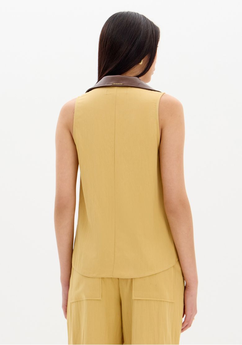 Look completo: modelo usando blusa sem mangas bege com amarração frontal combinada com calça pantalona bege