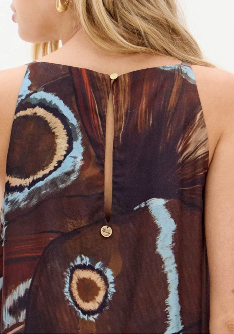 Detalhe das costas da blusa: abertura em gota com fechamento por um botão pequeno, acabamento em viscose estampada com motivos circulares.