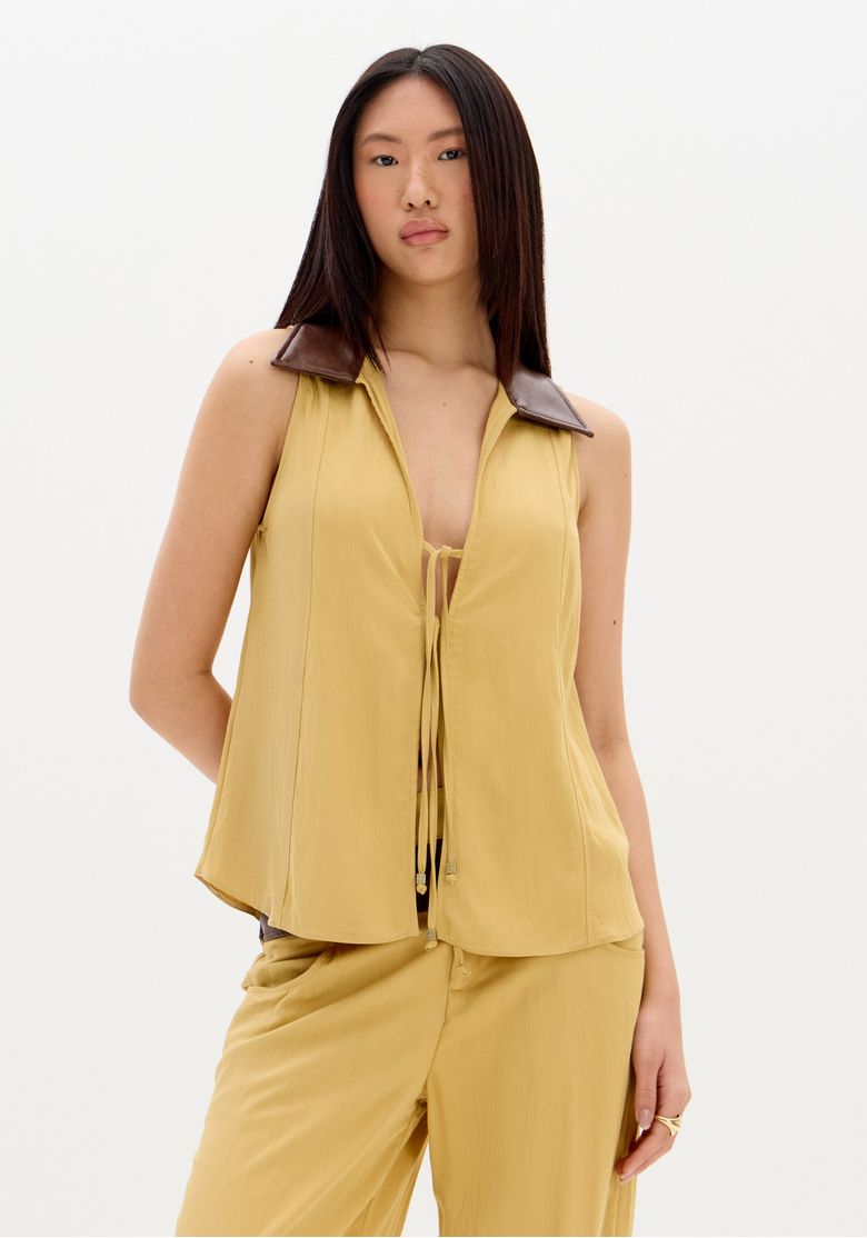 Close frontal da blusa sem mangas bege com gola marrom contrastante e amarração frontal, destaque no caimento fluido